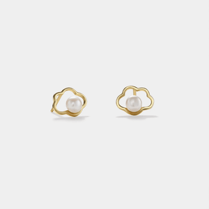 Gold earrings with pearl centers on a light gray background