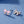 Pair of silver bow-shaped earrings with pink cubic zirconia on a blue background
