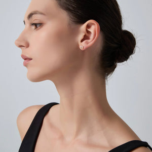Woman wearing a small earring on a plain background