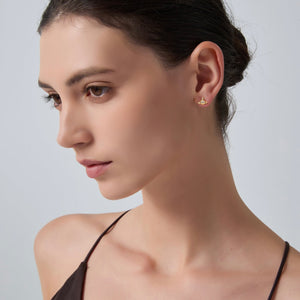 Close-up of a woman wearing a gold earring against a neutral background
