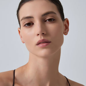Close-up of a woman wearing gold earrings against a light gray background