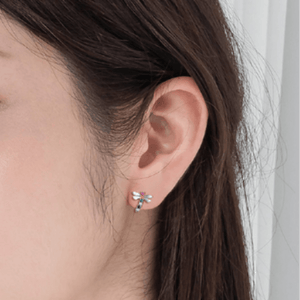 Close-up of an ear wearing a colorful earring with a neutral background