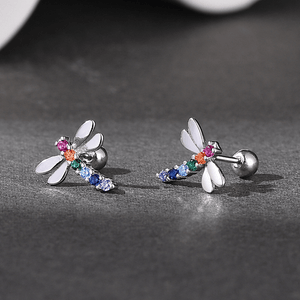 Dragonfly-shaped earrings with colorful gemstones on a dark surface