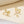 Gold bow-shaped earrings on a beige background