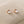 A pair of round moonstone stud earrings with gold plating, displayed on a beige surface.