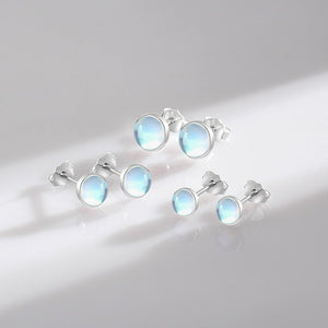 Set of silver earrings with light blue gemstones on a white background
