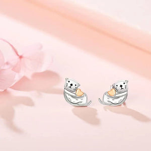 Pair of silver cat-shaped earrings on a soft pink background