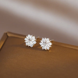Pair of silver floral earrings on a brown surface