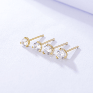Gold earrings with clear gemstones on a light gray background
