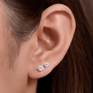 Close-up of an ear wearing two diamond stud earrings with a blurred background