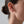 Close-up of an ear wearing a gold star-shaped earring against a neutral background