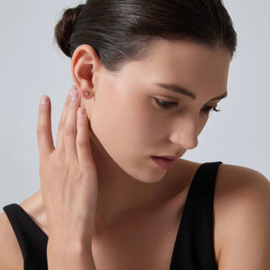 Woman wearing a gold earring on a plain background
