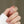 Star-shaped earrings held between fingers against a neutral background