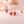 Strawberry-shaped earrings on a soft pink background