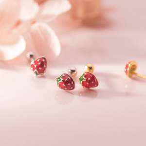 Strawberry-shaped earrings on a soft pink background