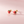 Strawberry-shaped earrings on a pink background