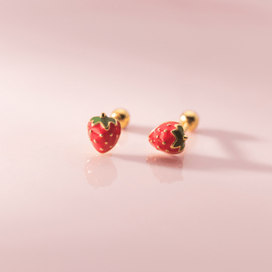 Strawberry-shaped earrings on a pink background