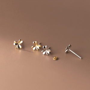 Set of four floral-shaped earrings on a brown background