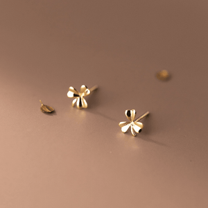 Gold flower-shaped earrings on a brown background