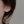 Gold flower earring worn by a person with a neutral background