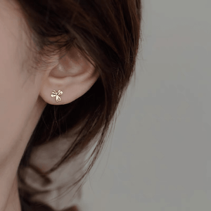 Gold flower earring worn by a person with a neutral background