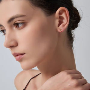 Close-up of a woman wearing a gold earring against a neutral background