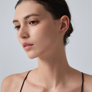 Close-up of a woman wearing a gold earring against a light gray background