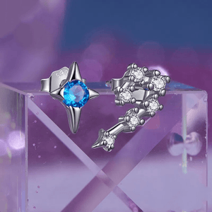 Silver earrings with blue gemstone and clear stones on a purple gradient background