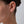Close-up of an ear wearing a diamond stud earring on a neutral background