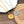 Two compass necklaces, one gold and one silver, on a wooden surface.