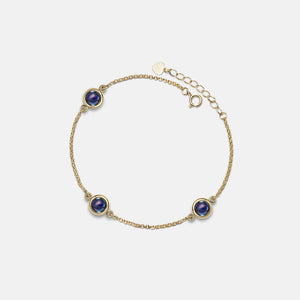 Gold bracelet with blue gemstones on a light gray background