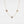 Gold necklace with three round gemstones on a light gray background