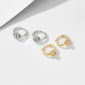 Two pairs of hoop earrings, one silver and one gold, on a light background.