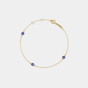 Gold bracelet with blue evil eye charms on a light gray background