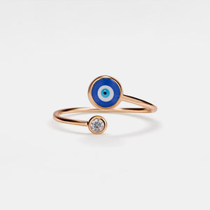 Rose gold ring with blue evil eye design on a white background