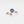 Gold ring with blue evil eye design on a white background