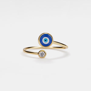Gold ring with blue evil eye design on a white background
