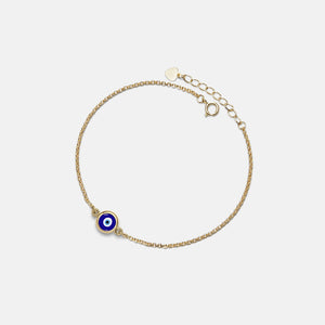 Gold bracelet with a blue evil eye charm on a light gray background