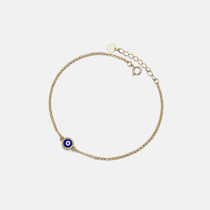 Gold bracelet with a blue evil eye charm on a light gray background