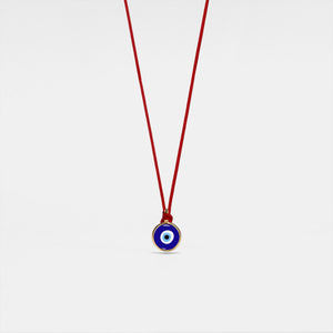 Evil eye pendant on a red string against a white background