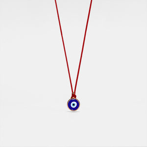 A red rope necklace with a blue circular charm representing the evil eye, hypoallergenic gold plating, and made from 925 sterling silver.