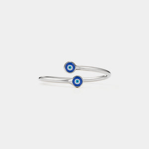Silver ring with blue evil eye charms on a light gray background