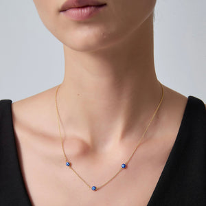 Necklace with blue stones worn by a person on a plain background