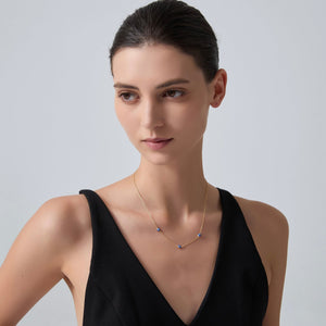 Woman wearing a delicate necklace against a plain background