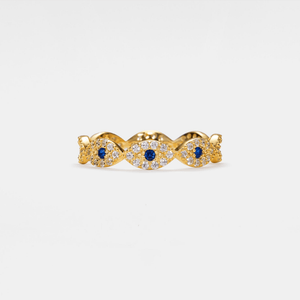 Gold evil eye ring with blue gemstones and diamond accents on a white background