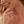Woman wearing a silver chain ring with a blue evil eye charm on a beige background