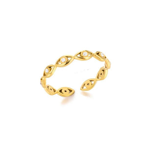 Gold evil eye ring with colorless gemstones on a beige background
