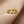 Gold evil eye ring with green gemstones on a beige background