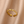 Gold evil eye ring with colorless gemstone accents on a beige fabric background
