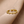 Gold evil eye ring with colorless gemstones on a beige background